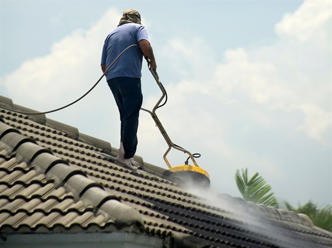 A person cleaning a roof with a pressure washer in Wilmington, NC.