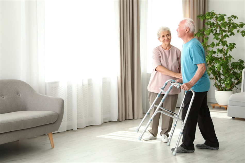 Man using a standard walker to walk across his living room.